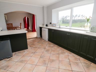 A kitchen with tiled floor dark cabinets white countertops by a large window with a sink and a radio at Whiteadder Bank in Berwick-Upon-Tweed