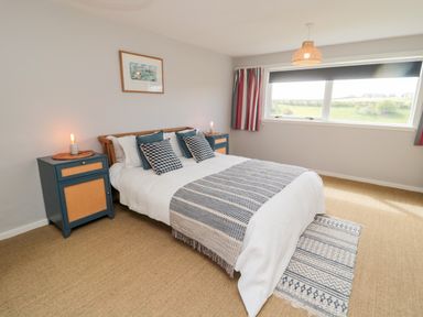 A bedroom with a bed two bedside tables a window and a rug at Whiteadder Bank in Berwick-Upon-Tweed