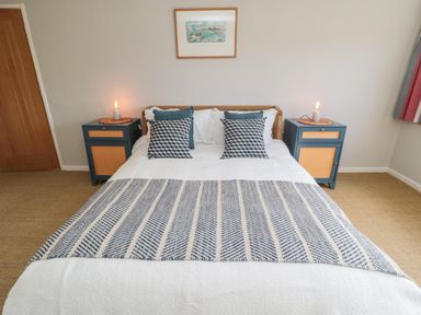 A bedroom with a bed with patterned pillows and a blanket with two bedside tables with lamps at Whiteadder Bank in Berwick-Upon-Tweed