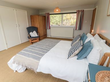 A bedroom with a bed with pillows and blanket a wardrobe a chair with towels and a window at Whiteadder Bank in Berwick-Upon-Tweed