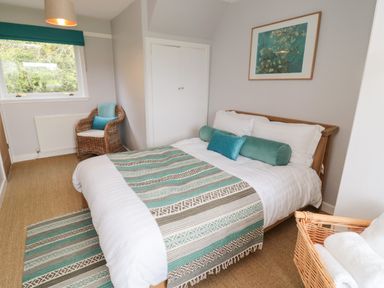 A bedroom with a double bed a wicker chair a window and a basket with towels at Whiteadder Bank in Berwick-Upon-Tweed