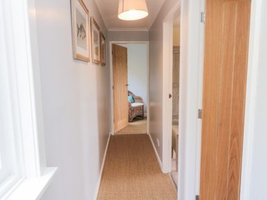 A hallway with wooden doors and a wicker chair visible through an open door at Whiteadder Bank in Berwick-Upon-Tweed