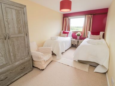 A bedroom with two single beds a wooden wardrobe and a chair at Whiteadder Bank in Berwick-Upon-Tweed