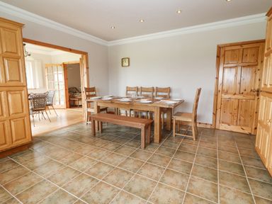 A dining room with a wooden table and chairs set for a meal at Cloughoge House in Kilrush County Clare