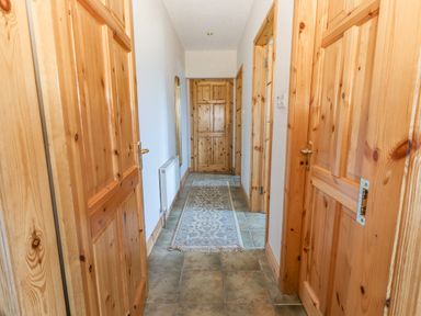 A hallway with wooden doors tiled floor a radiator and a rug at Cloughoge House in Kilrush County Clare