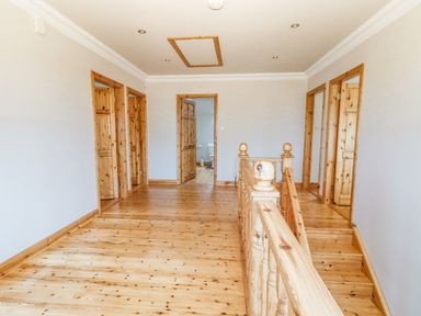A hallway with wooden floors and doors and a wooden staircase railing at Cloughoge House in Kilrush County Clare