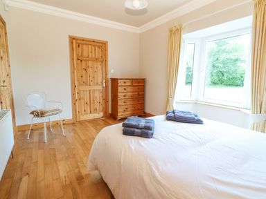 A bedroom with a wooden dresser a chair and towels on a bed at Cloughoge House in Kilrush County Clare