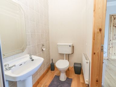 A small bathroom with a white sink and mirror on the left a toilet in the center and a radiator on the right at Cloughoge House Kilrush County Clare