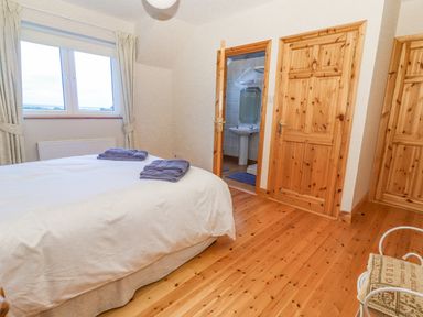 A bedroom with a bed and folded towels near a window and wooden doors at Cloughoge House Kilrush County Clare