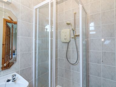 A bathroom with a corner shower enclosure a white sink and a wall mirror at Cloughoge House Kilrush County Clare