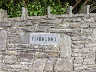 Stone wall with a sign reading Cloughoge surrounded by green foliage at Cloughoge House in Kilrush County Clare