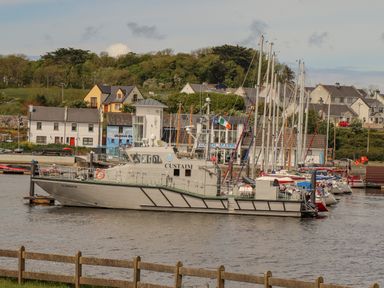 A customs patrol boat docked at a marina with sailboats and houses in the background at Cloughoge House in Kilrush County Clare