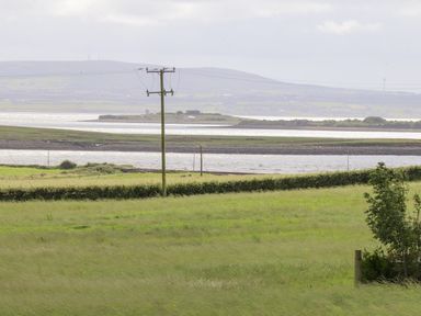 A landscape with green fields water bodies and hills in the distance at Cloughoge House in Kilrush County Clare