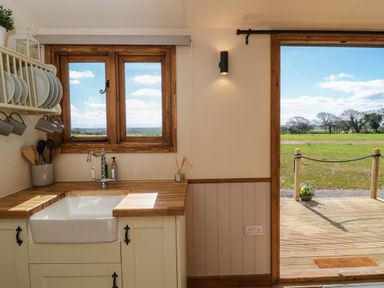 A kitchen sink area with wooden counters and a window overlooking a field at Buzzards in Morchard Bishop