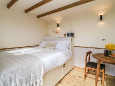 A bedroom with a bed white bedding a wooden table and chair with flowers at Buzzards in Morchard Bishop