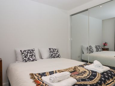 A bedroom with a bed with pillows and towels in front of a mirrored wardrobe at Narracott Down in South Molton