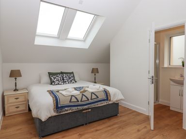 A bedroom with a double bed bedside tables lamps and an open door leading to a bathroom at Narracott Down South Molton