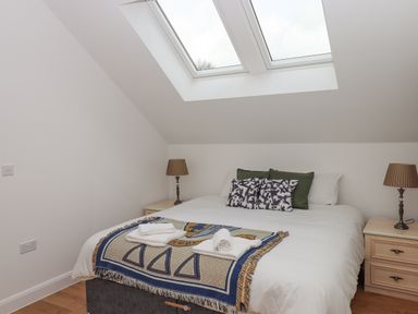 A bedroom with a double bed under skylight windows with side tables and lamps at Narracott Down in South Molton