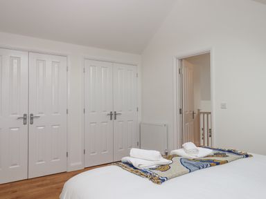 A bedroom with folded towels on a bed and double doors leading to closets at Narracott Down in South Molton