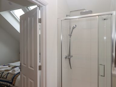 A bathroom with a glass shower enclosure and a showerhead next to an open door leading to a bedroom at Narracott Down in South Molton