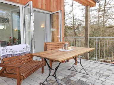 An outdoor patio with wooden benches and a table with a coffee pot and cup at Narracott Down in South Molton