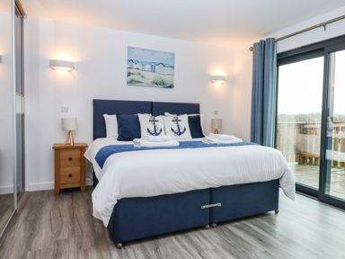 A bedroom with a blue bed frame white bedding and anchor-themed pillows at Strawberry Bank - Nuthatch in Pyworthy near Bridgerule
