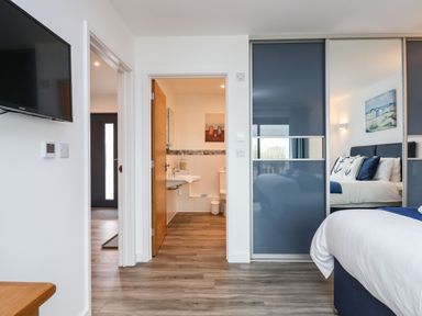 A bedroom with a bed and mirrored sliding wardrobe doors at Strawberry Bank - Nuthatch in Pyworthy near Bridgerule