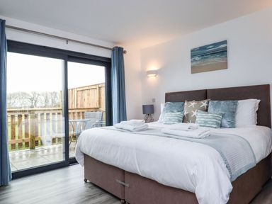 A bedroom with a large bed and sliding glass doors leading to a patio at Strawberry Bank - Nuthatch in Pyworthy near Bridgerule