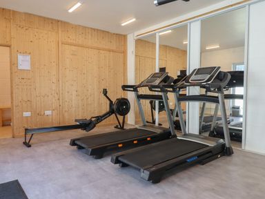 A gym room with two treadmills and a rowing machine against a wooden wall with mirrors at Strawberry Bank - Nuthatch in Pyworthy near Bridgerule