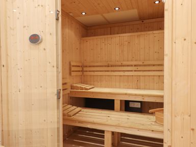An interior of a wooden sauna with benches and a bucket at Strawberry Bank - Nuthatch in Pyworthy near Bridgerule