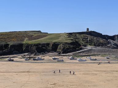 A beach with people walking dogs boats on sand and rocky cliffs in the background at Strawberry Bank - Nuthatch in Pyworthy near Bridgerule