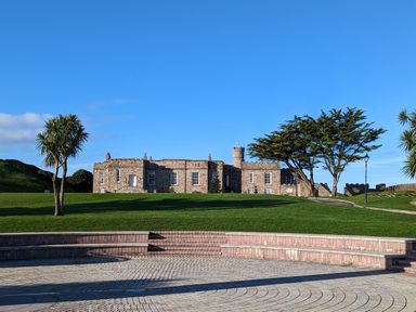 A stone building with trees and green grass under a blue sky