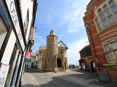 A street view with old stone and brick buildings and a tower in Lyme Regis
