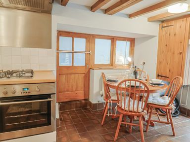 A kitchen with a dining table and chairs at Riverdance Cottage in Lyme Regis