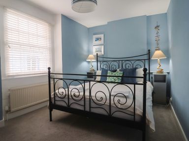 A bedroom with a black bed frame and lamps at Riverdance Cottage in Lyme Regis