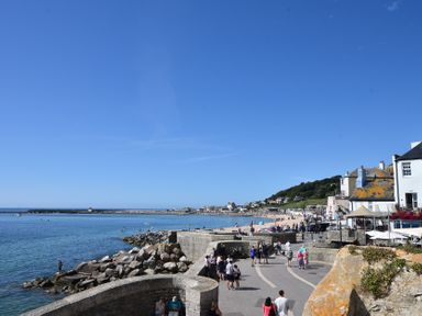A beach area with people walking near water at Riverdance Cottage Lyme Regis