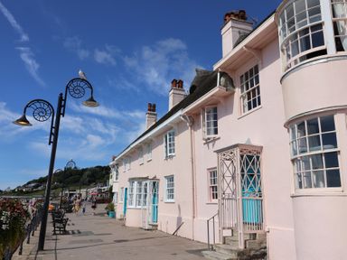 A building with benches and flowers along a walkway at Riverdance Cottage in Lyme Regis