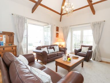 A living room with brown leather sofas a wooden coffee table and a wooden cabinet at Farnelea in West Fleetham near Seahouses