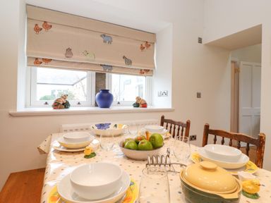 A dining table set with bowls and glasses near a window with animal patterned blinds at Farnelea in West Fleetham near Seahouses
