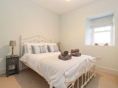 A bedroom with a white metal bed frame two bedside tables with lamps and a window at Farnelea West Fleetham near Seahouses
