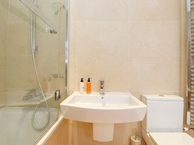 A bathroom with a bathtub shower combo sink with soap dispensers and a toilet at Farnelea West Fleetham near Seahouses