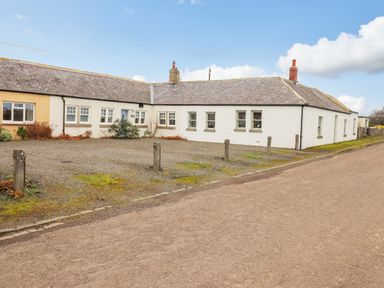 An exterior view of a single-story building with white walls and multiple windows at farnelea west fleetham near seahouses