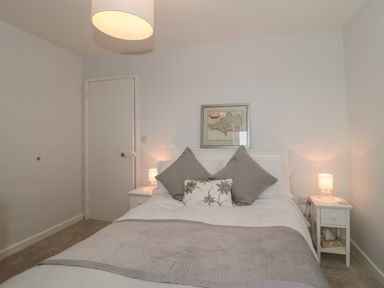 A bedroom with a bed with pillows and blanket beside two bedside tables with lamps and a framed map on the wall at Scrambles Cottage in Stoke-Sub-Hamdon Somerset
