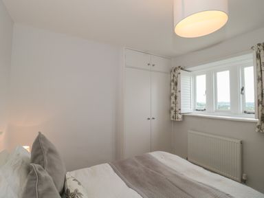 A bedroom with bed pillows a window with curtains built in wardrobe and a radiator at Scrambles Cottage in Stoke-Sub-Hamdon Somerset