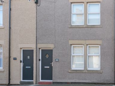 Two adjacent houses with dark doors and four white framed windows at 4 Percy Street in Amble