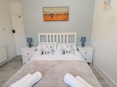 A bedroom with a white bed and two pillows with house prints with bedside tables and lamps at 4 Percy Street in Amble