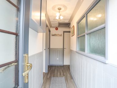 A hallway with a gray wooden floor and doors at Cae Ffynnon in Star near Gaerwen
