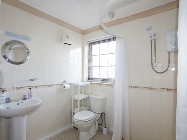 A bathroom with a toilet sink shower and shelving unit at Cae Ffynnon Star near Gaerwen