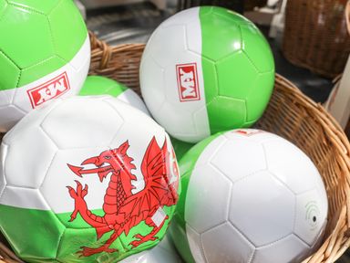 A basket filled with green and white soccer balls including one with a red dragon design at Cae Ffynnon Star near Gaerwen