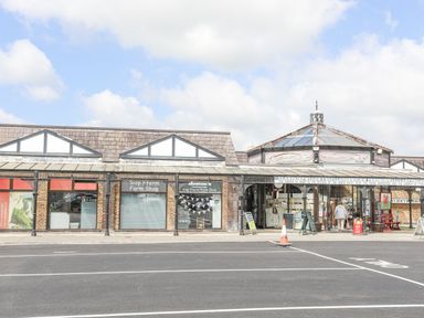 A brick building with a farm shop and an entrance with signs and a person walking inside at Cae Ffynnon in Star near Gaerwen